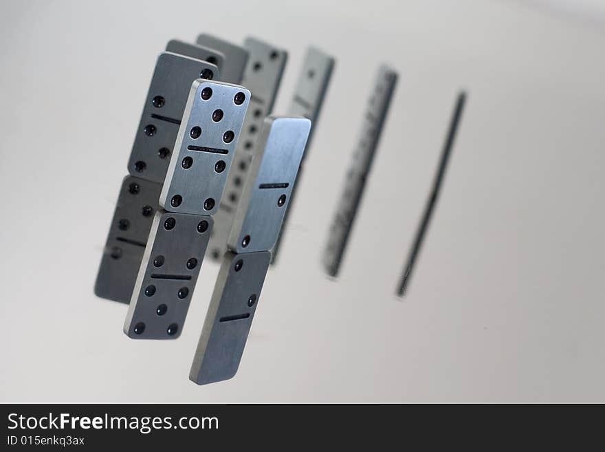 Steel dominoes in a row with reflection in polished surface