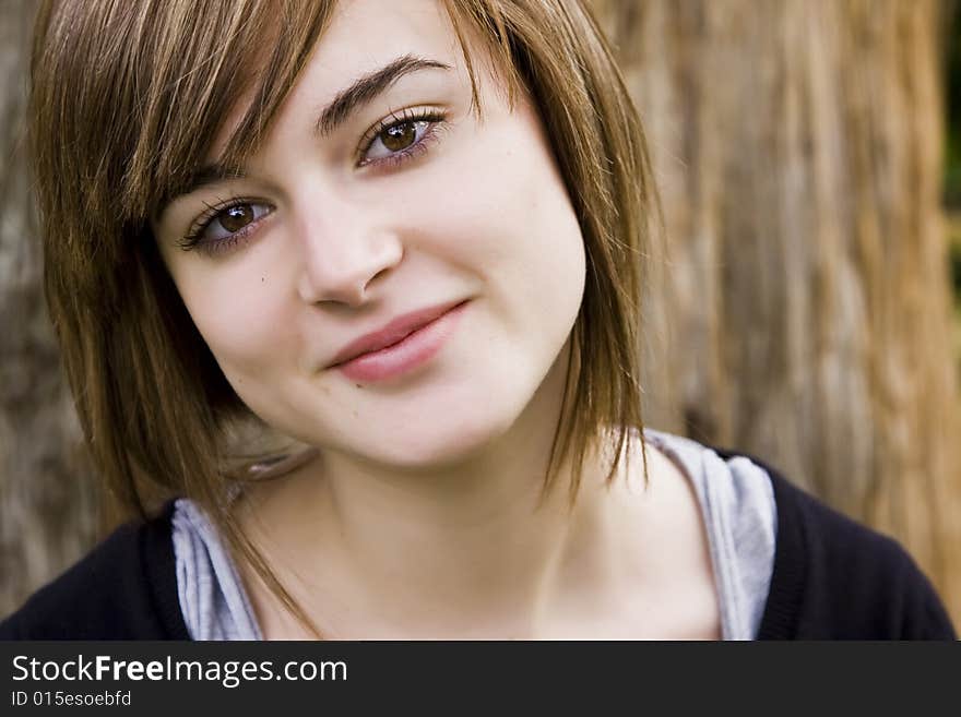 Young woman close portrait with tree trunk as background