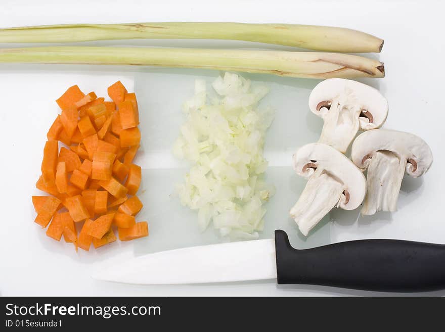 Sliced carrots, onions and champignons on a glass chopping board. Sliced carrots, onions and champignons on a glass chopping board