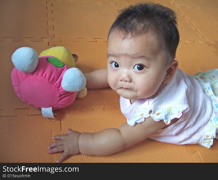 Lovely big eyes baby and toy on a yellow mat. Lovely big eyes baby and toy on a yellow mat