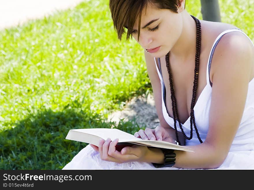 Beautiful blond woman reading over the grass