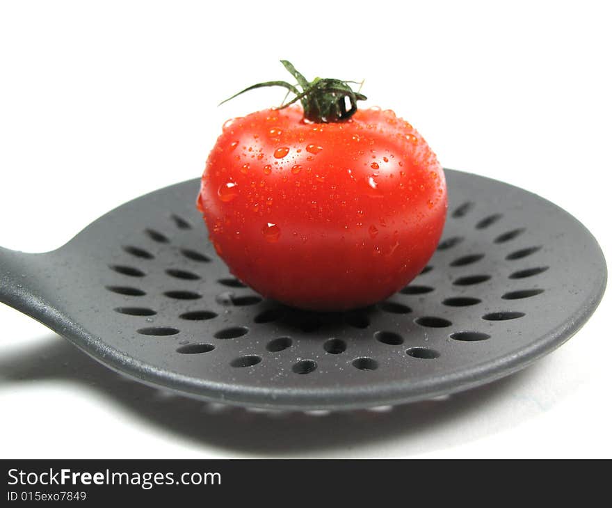 A ripe tomato on a kitchentool. A ripe tomato on a kitchentool