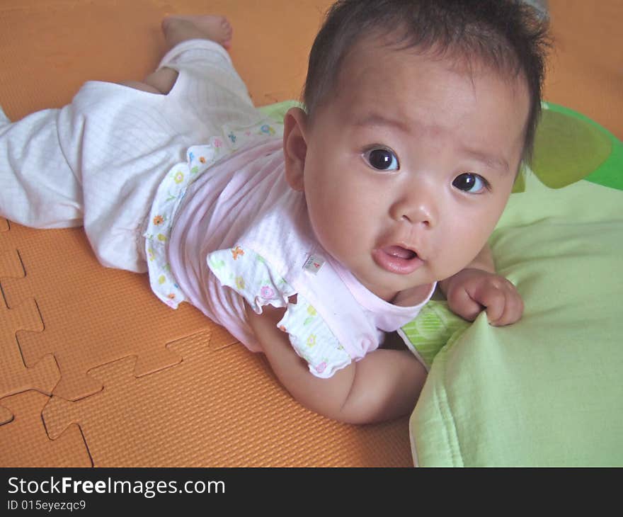 Lovely big eyes baby on a yellow mat. Lovely big eyes baby on a yellow mat