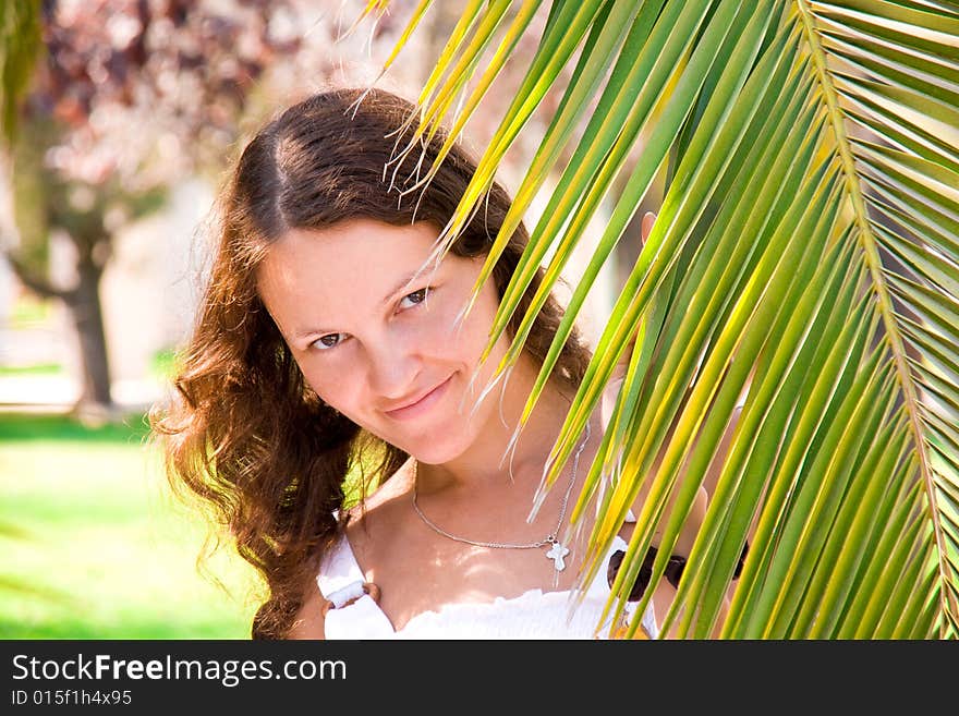 Joyful girl behind a palm branch, Valencia, Spain