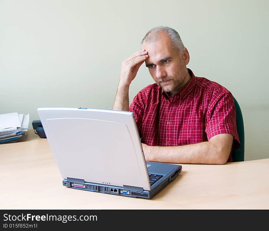 Thoughtful office worker working at the desk with laptop