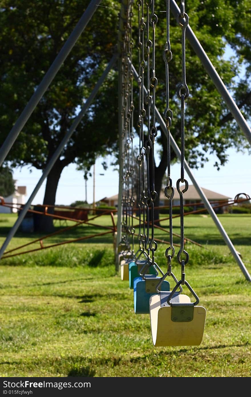 A row of playground swings awaiting the arrival of children on their way home from school. A row of playground swings awaiting the arrival of children on their way home from school.