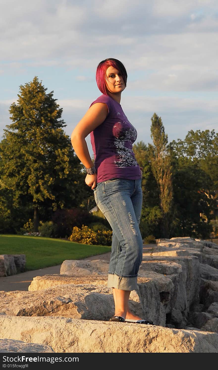 An red hair girl in jeans standing on the shore of lake Ontario at sunset. An red hair girl in jeans standing on the shore of lake Ontario at sunset.