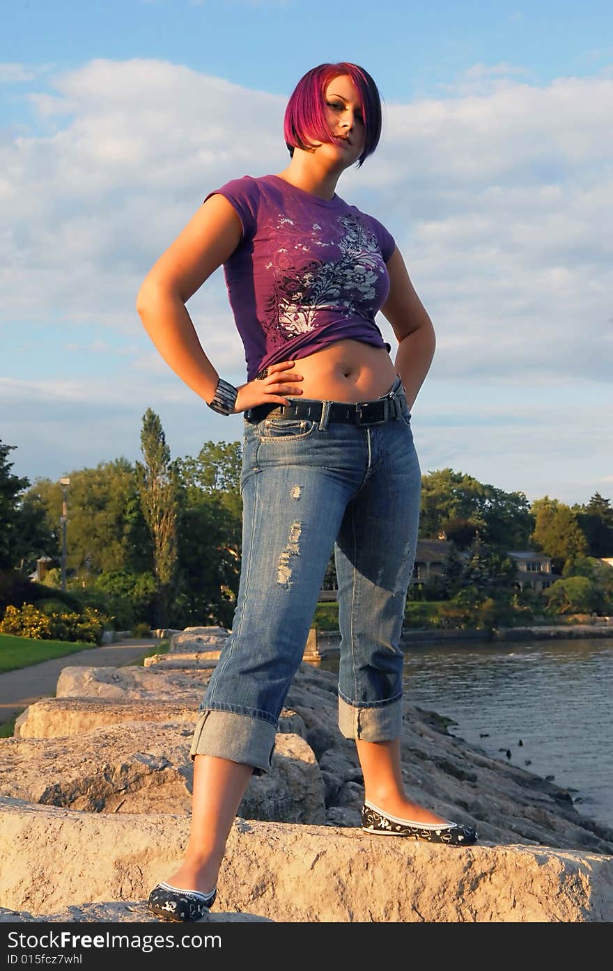 An red hair girl in jeans standing on the shore of lake Ontario at sunset. An red hair girl in jeans standing on the shore of lake Ontario at sunset.