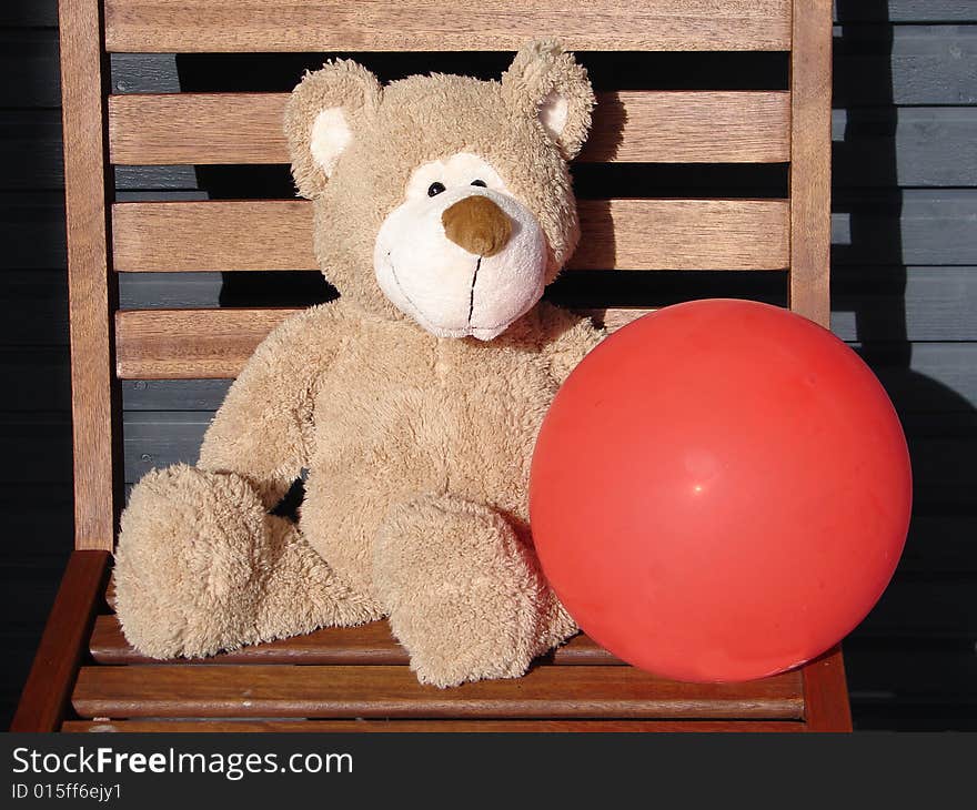 Toy teddy bear holds a red balloon