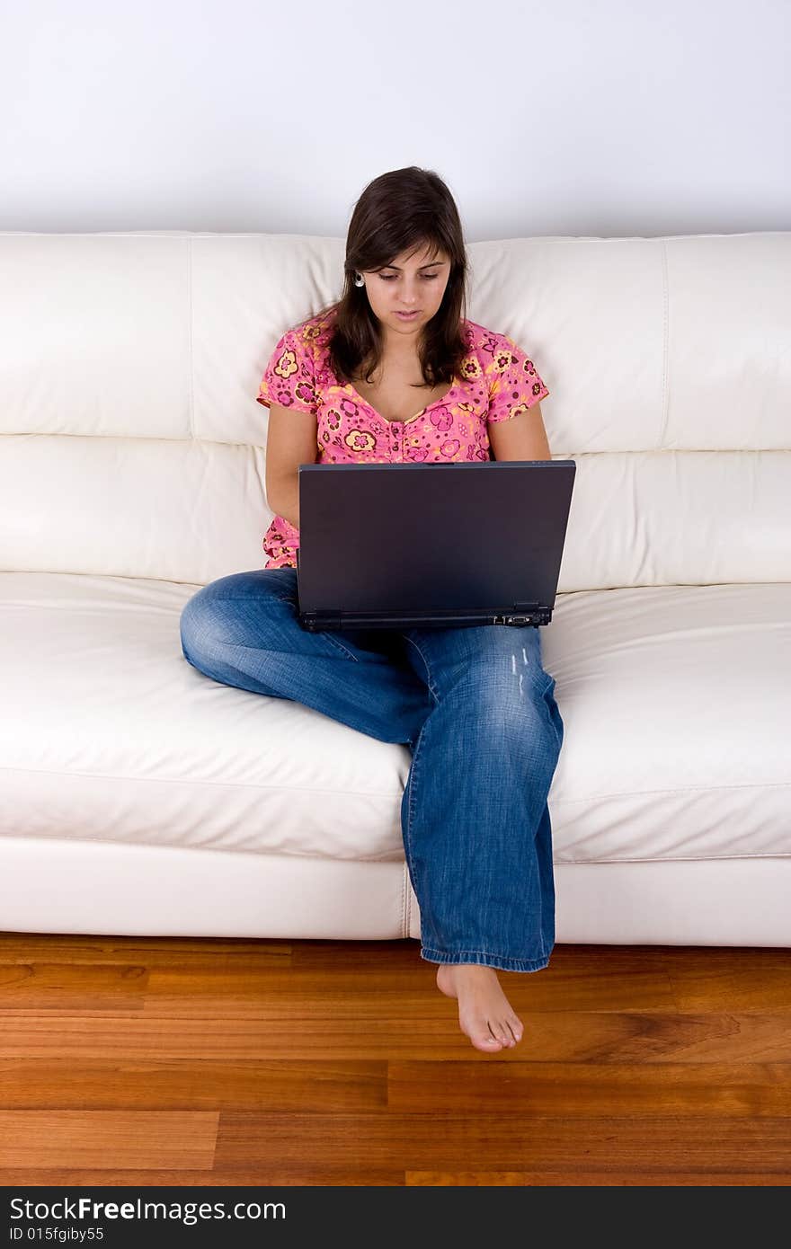 Beautiful young woman with laptop on sofa