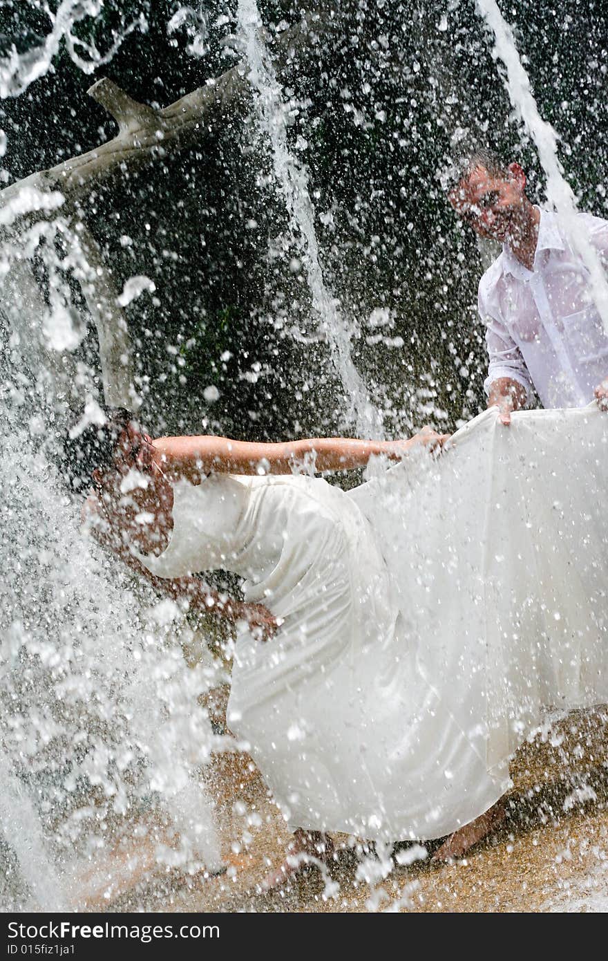 Bride and groom dancing under a water fountain on their wedding day. Bride and groom dancing under a water fountain on their wedding day.