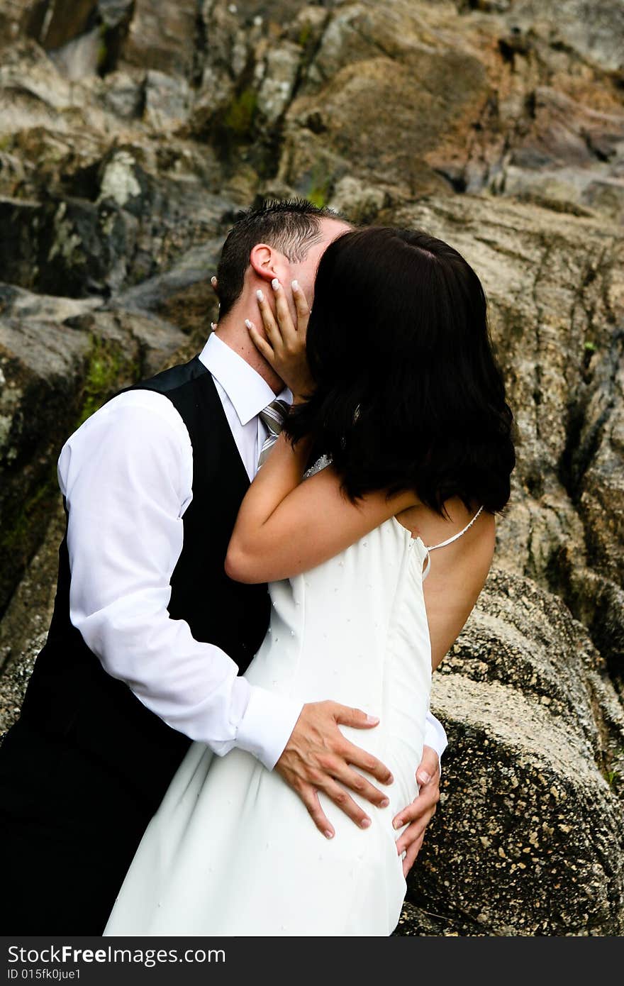 Happy bride and groom kissing on top of a mountain. Happy bride and groom kissing on top of a mountain.