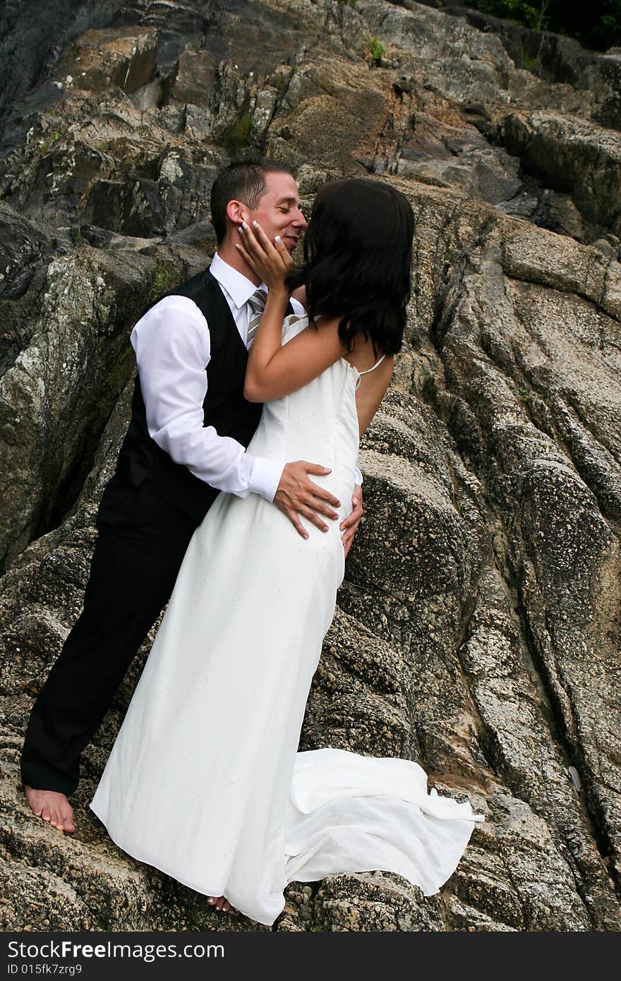 Happy bride and groom kissing on top of a mountain. Happy bride and groom kissing on top of a mountain.