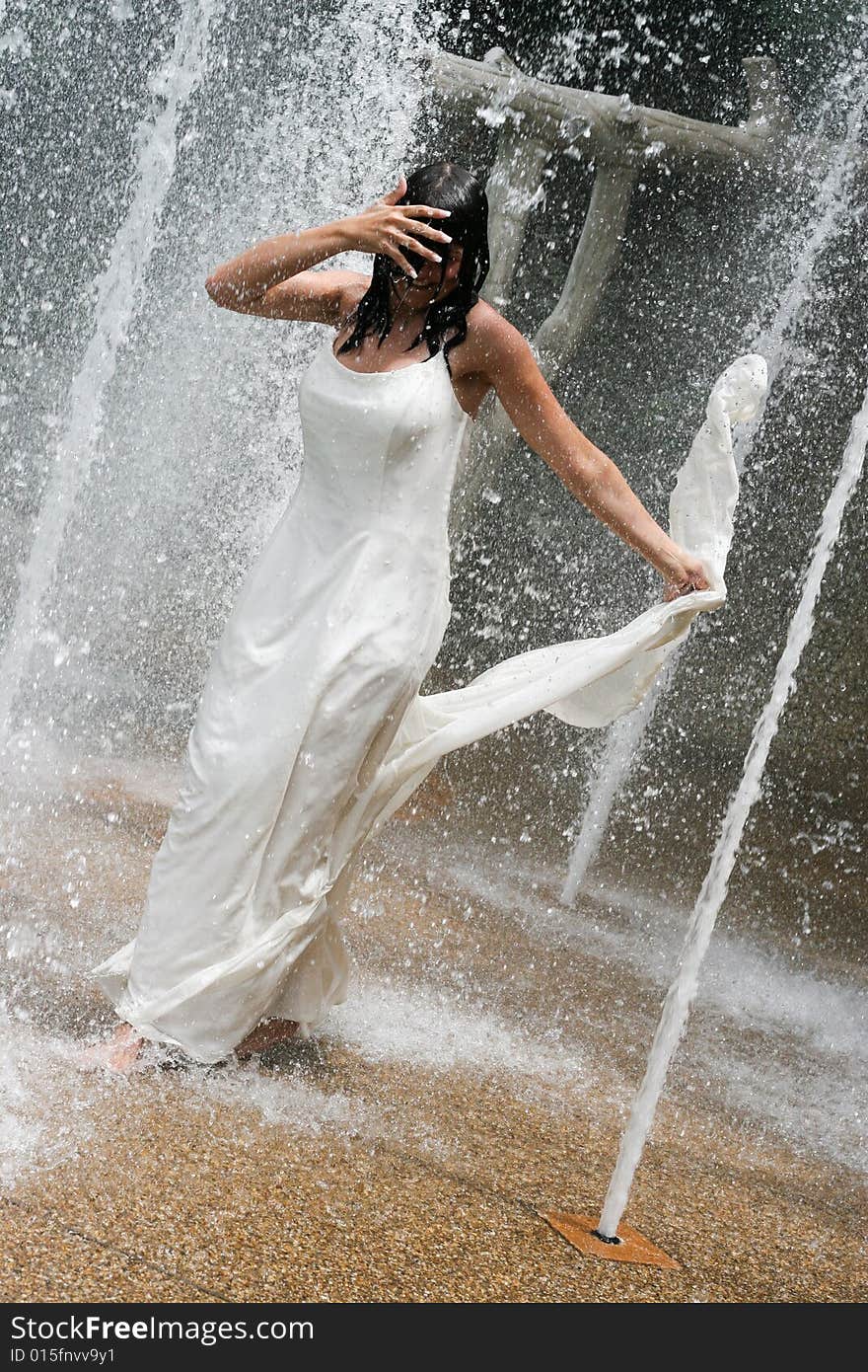 Beautiful young bride playing in a waterfall on her wedding day. Beautiful young bride playing in a waterfall on her wedding day.