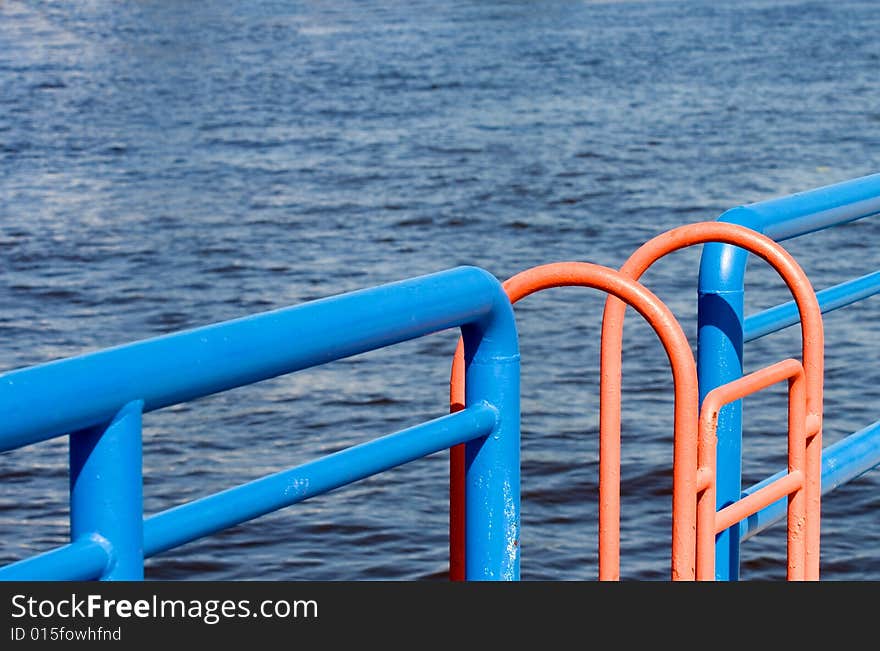 An orange ladder interrupts the straight blue line of the rails along a Great Lakes channel wall