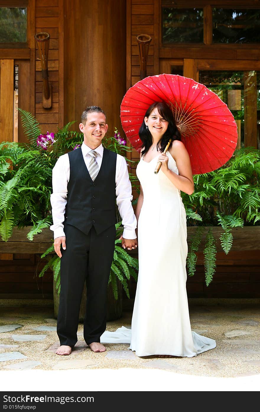 Groom with his bride carrying a red Asian umbrella. Groom with his bride carrying a red Asian umbrella.