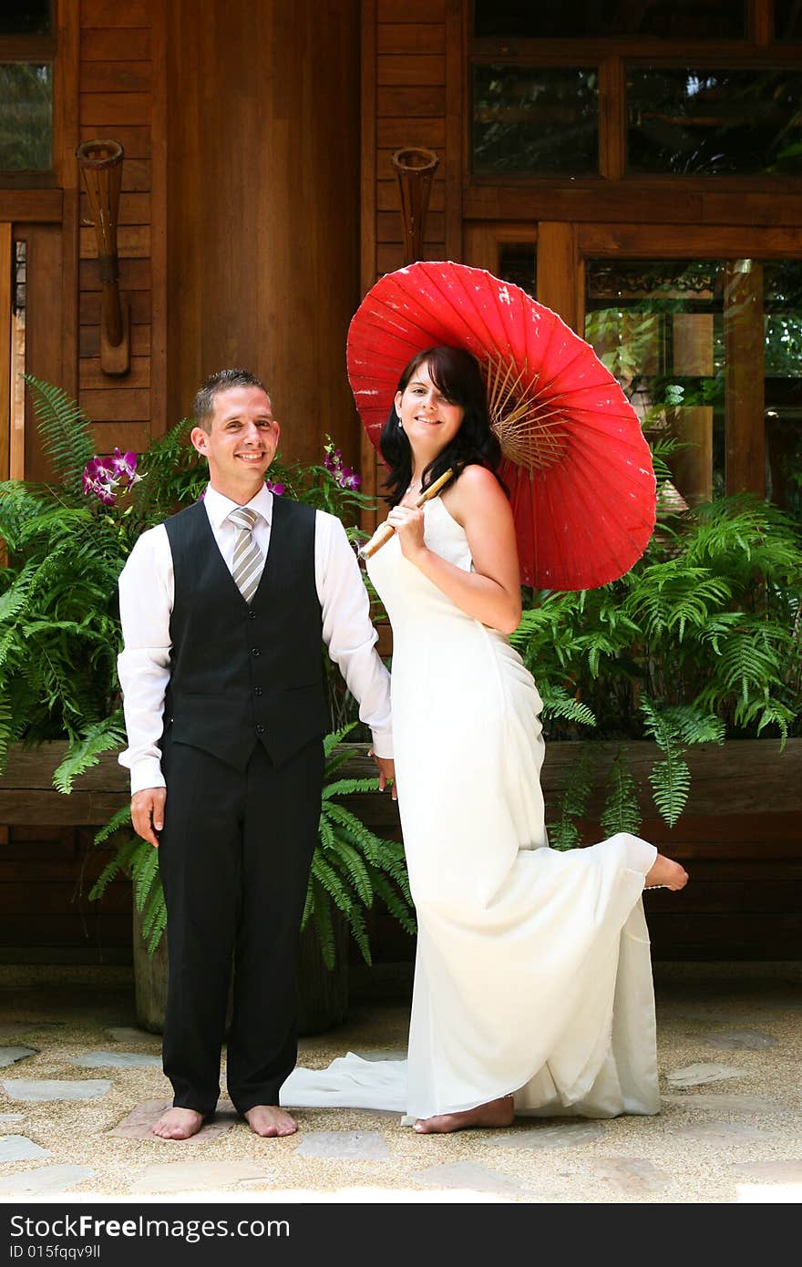 Groom with his bride carrying a red Asian umbrella. Groom with his bride carrying a red Asian umbrella.