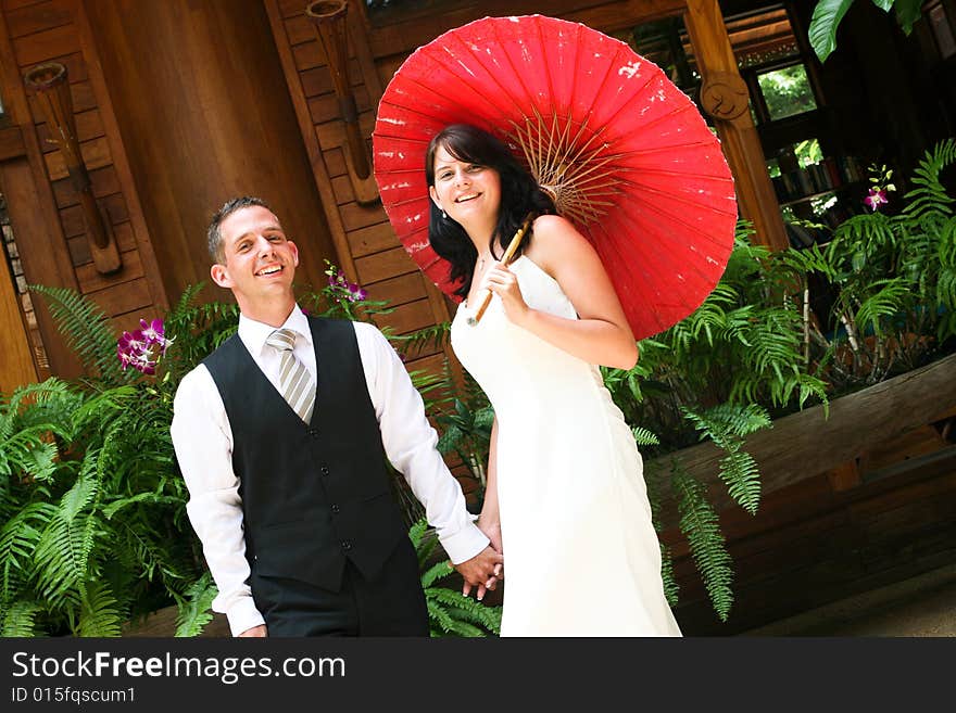 Groom with his bride carrying a red Asian umbrella. Groom with his bride carrying a red Asian umbrella.