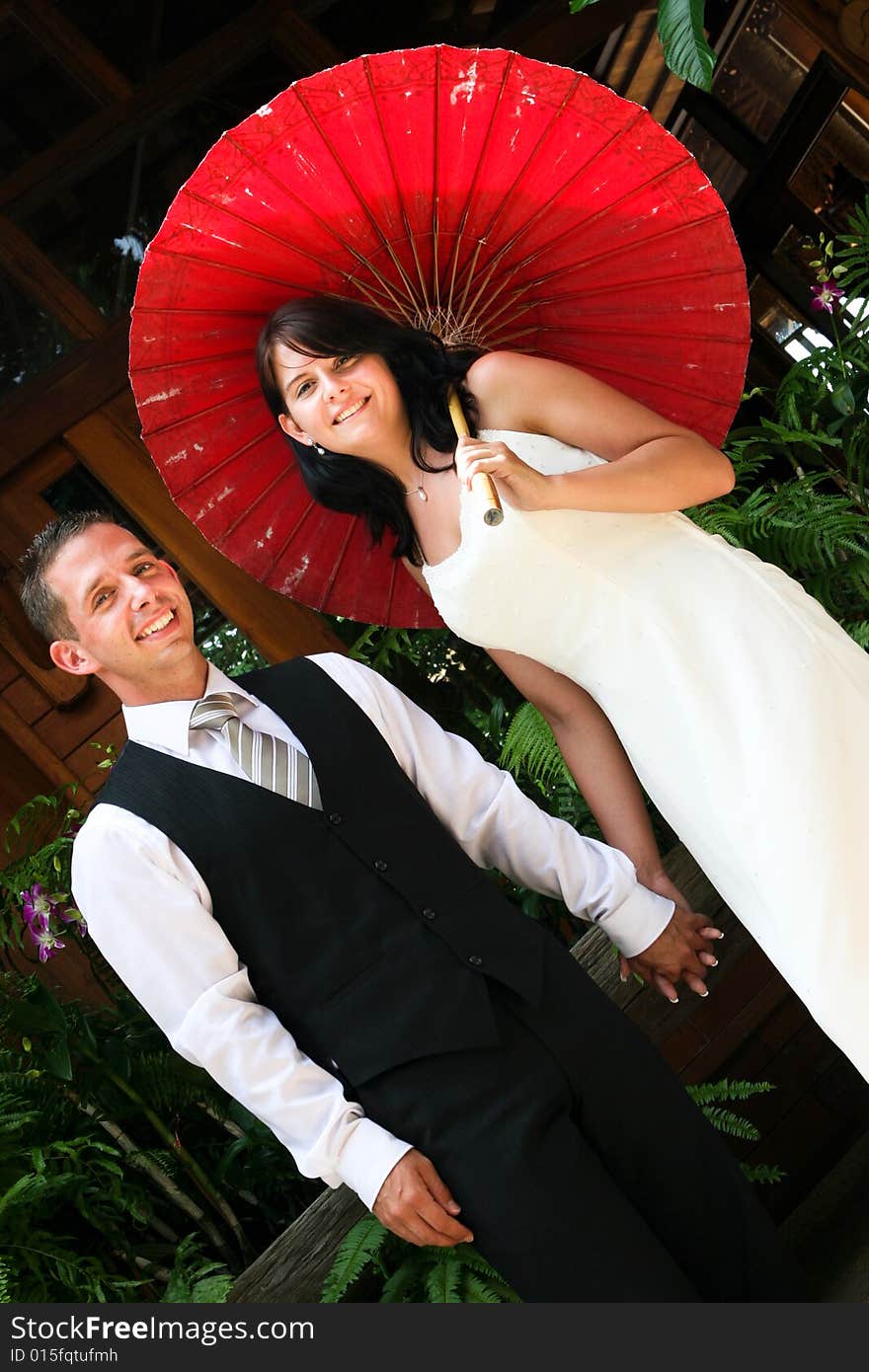 Groom with his bride carrying a red Asian umbrella. Groom with his bride carrying a red Asian umbrella.