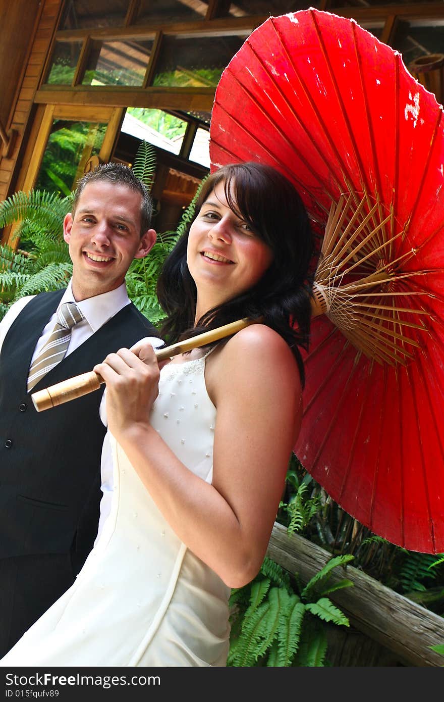 Groom with his bride carrying a red Asian umbrella. Groom with his bride carrying a red Asian umbrella.