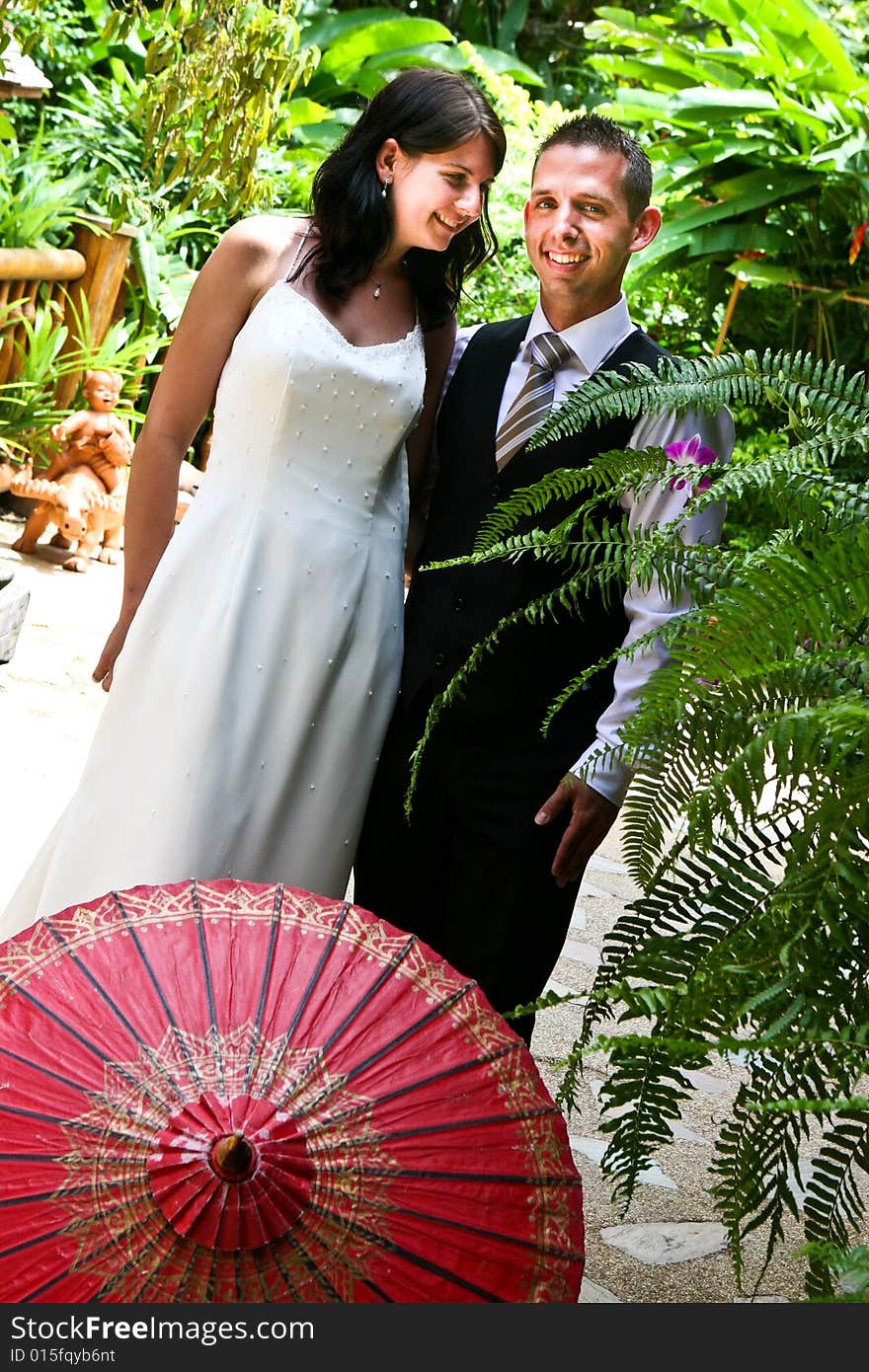 Groom with his bride carrying a red Asian umbrella. Groom with his bride carrying a red Asian umbrella.