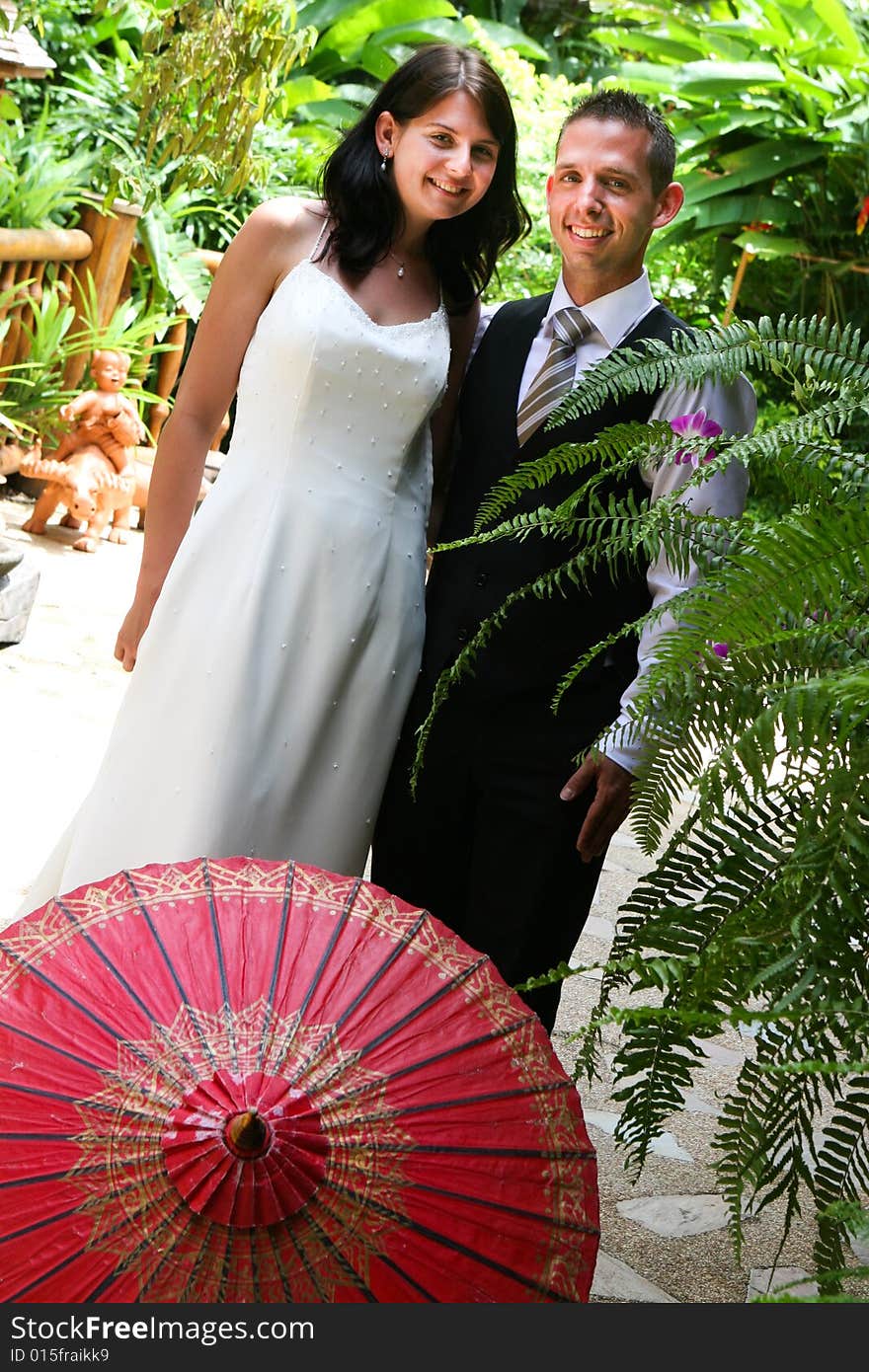 Groom with his bride carrying a red Asian umbrella. Groom with his bride carrying a red Asian umbrella.