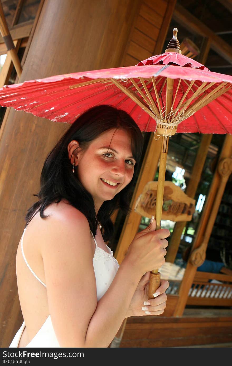 Portrait of a beautiful brunette bride with a red parasol. Portrait of a beautiful brunette bride with a red parasol.