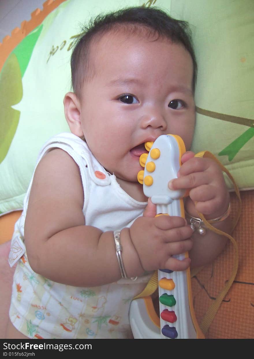 Happy baby and toy on a green pillow