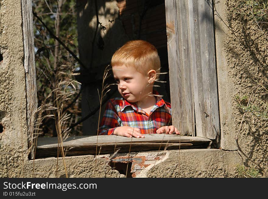 A three-and-a-half year old boy looks out of a window of an abandoned, single-room schoolhouse. A three-and-a-half year old boy looks out of a window of an abandoned, single-room schoolhouse.