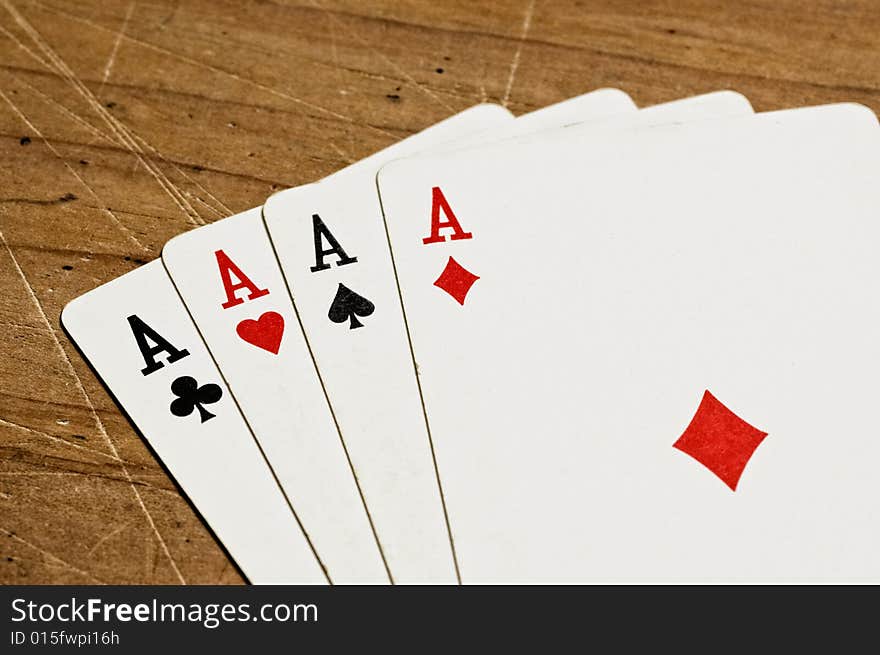 Four aces over an old wooden table, close up.