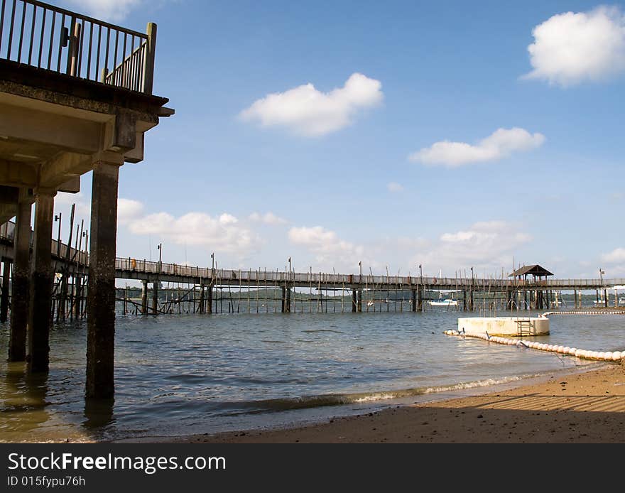 Boardwalk curving around a beach creating a man made lagoon, in a partly cloudy sky. Boardwalk curving around a beach creating a man made lagoon, in a partly cloudy sky