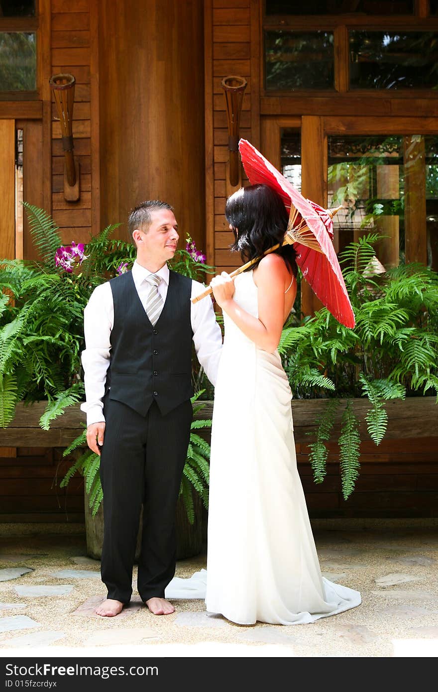 Groom with his bride carrying a red Asian umbrella. Groom with his bride carrying a red Asian umbrella.