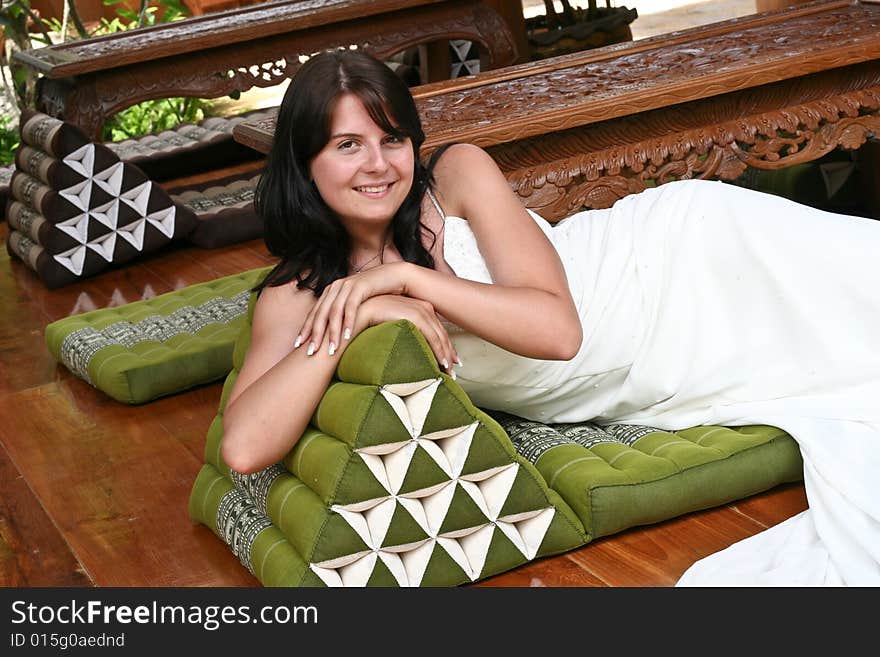 Beautiful young bride relaxing on a Thai cushion.