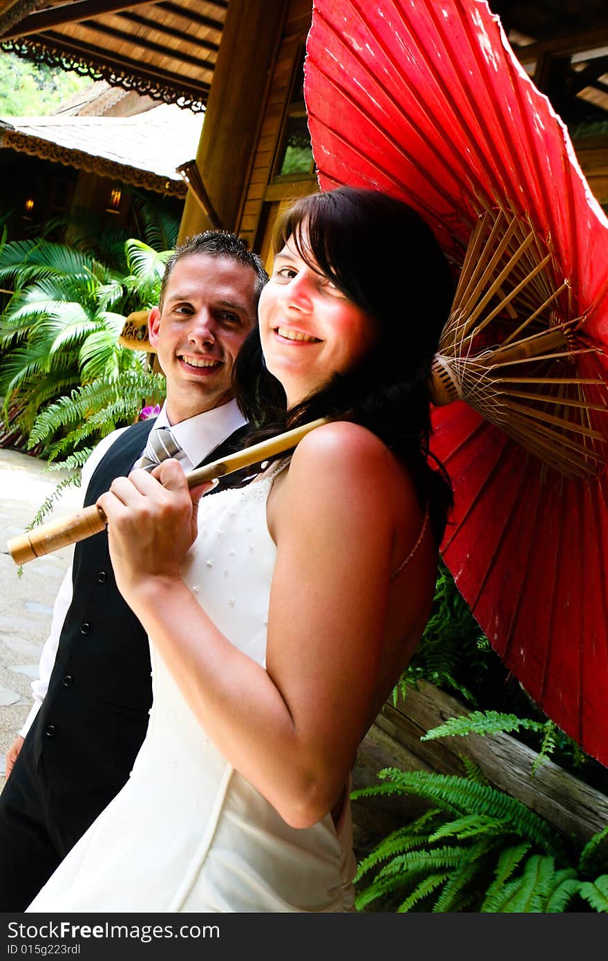 Groom with his bride carrying a red Asian umbrella. Groom with his bride carrying a red Asian umbrella.