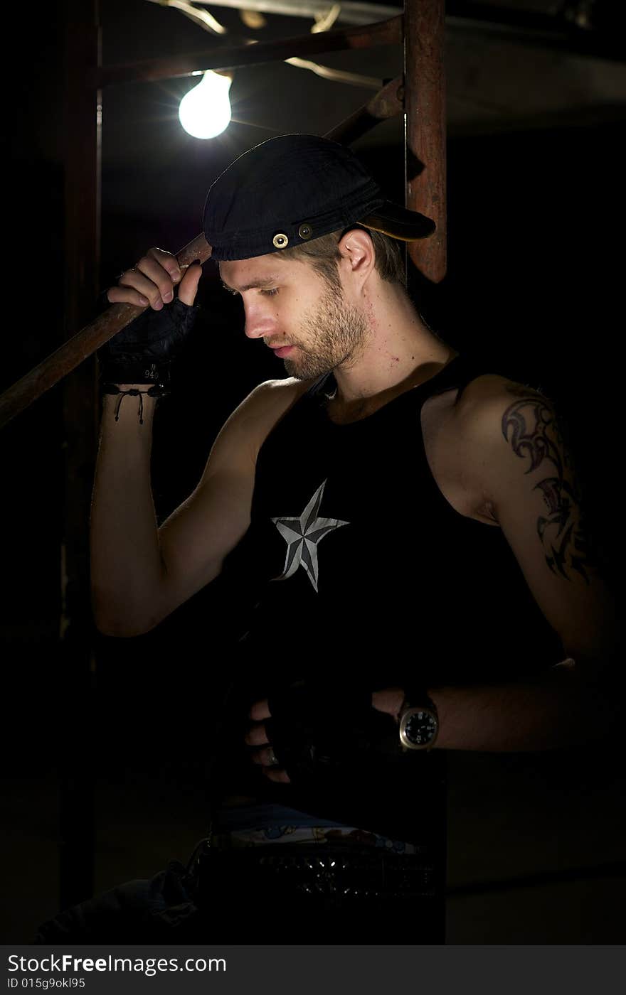 Young fellow in the tattooings stands near the lamp