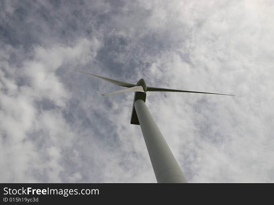 A wind turbine against a calm cloudy sky. A wind turbine against a calm cloudy sky