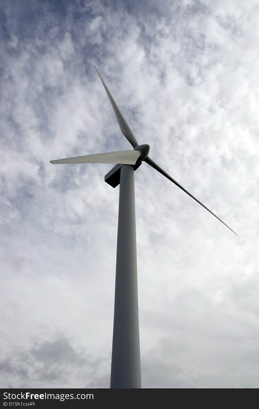 A wind turbine against a calm cloudy sky. A wind turbine against a calm cloudy sky