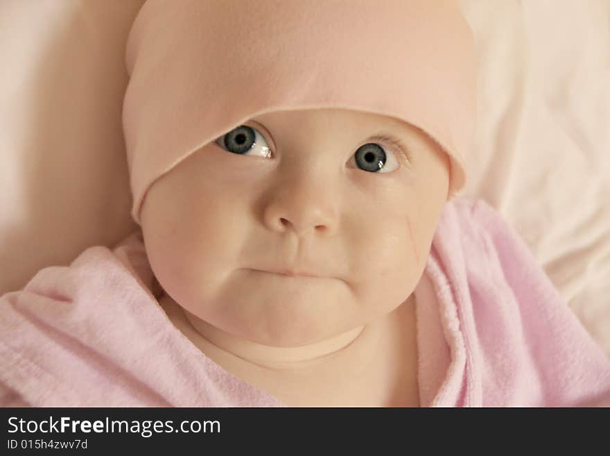 Cute big-eyed baby girl looking up with curious facial expression, space for text