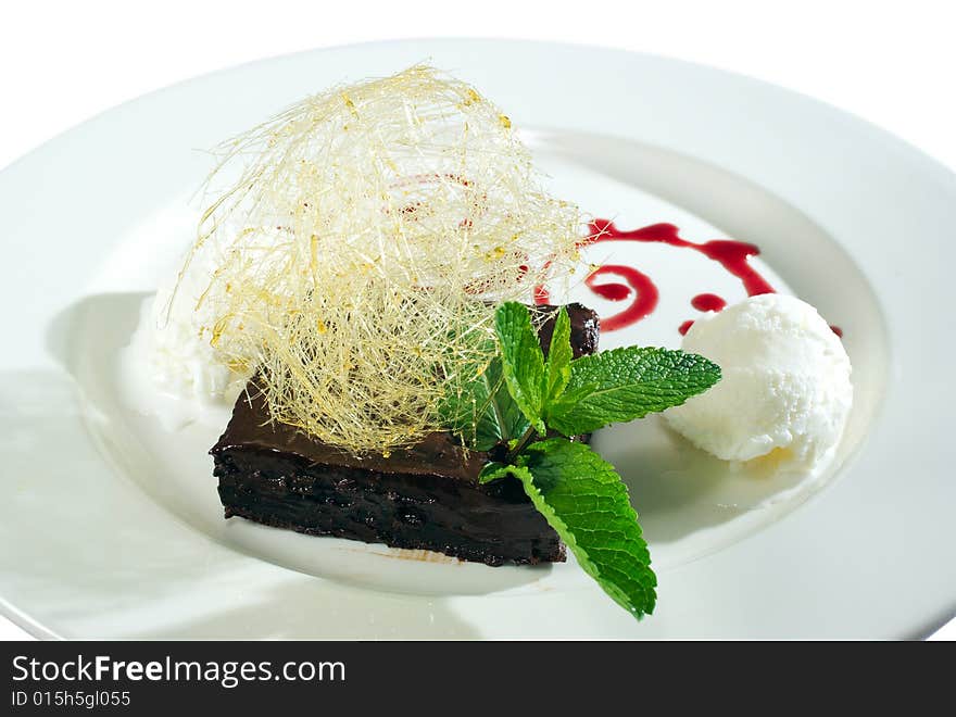 Chocolate dessert and icecream decorated with strands of burned sugar and mint leaves isolated on white