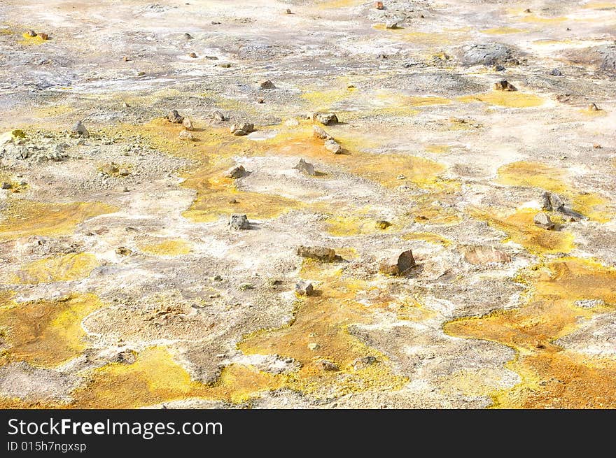 Colorful suplhur landscape. Small rocks lying around. Orange yellow soil.