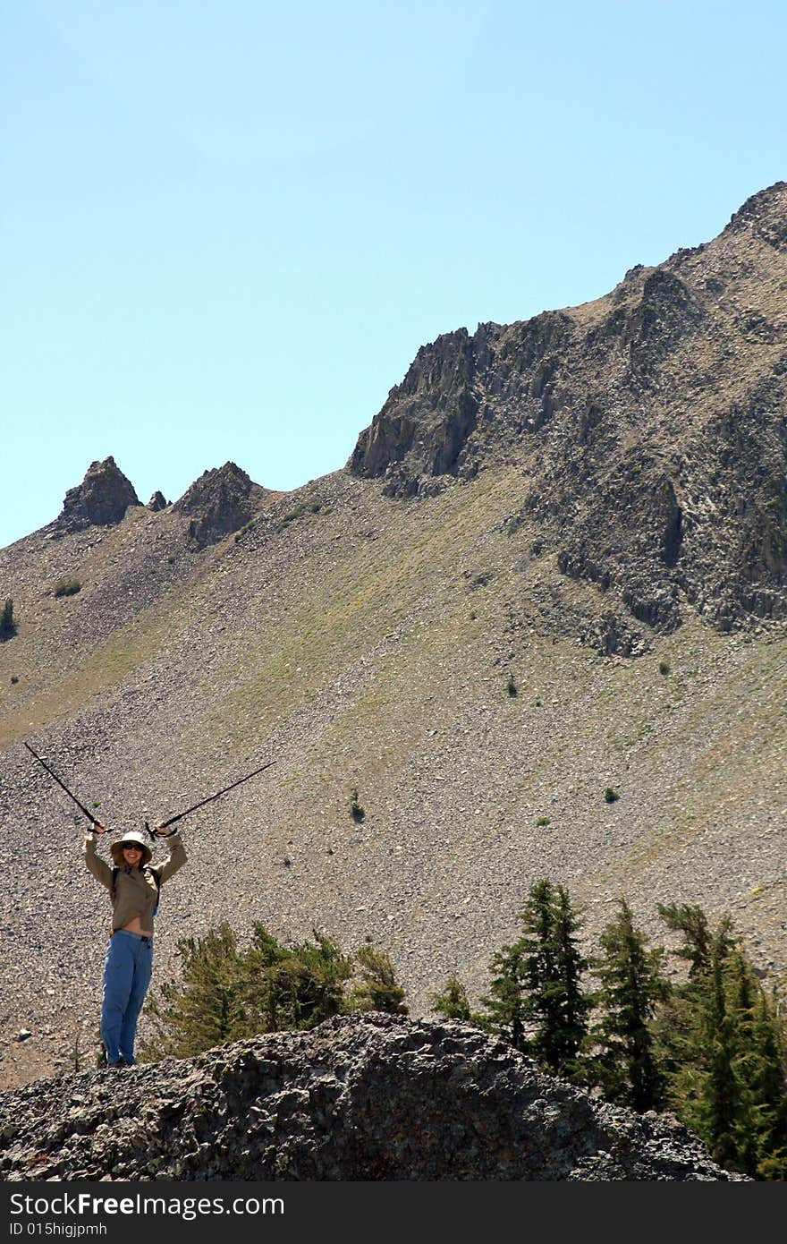 A young woman with hiking poles in the air celebrating her climbing victory.  California, U.S.A. A young woman with hiking poles in the air celebrating her climbing victory.  California, U.S.A.