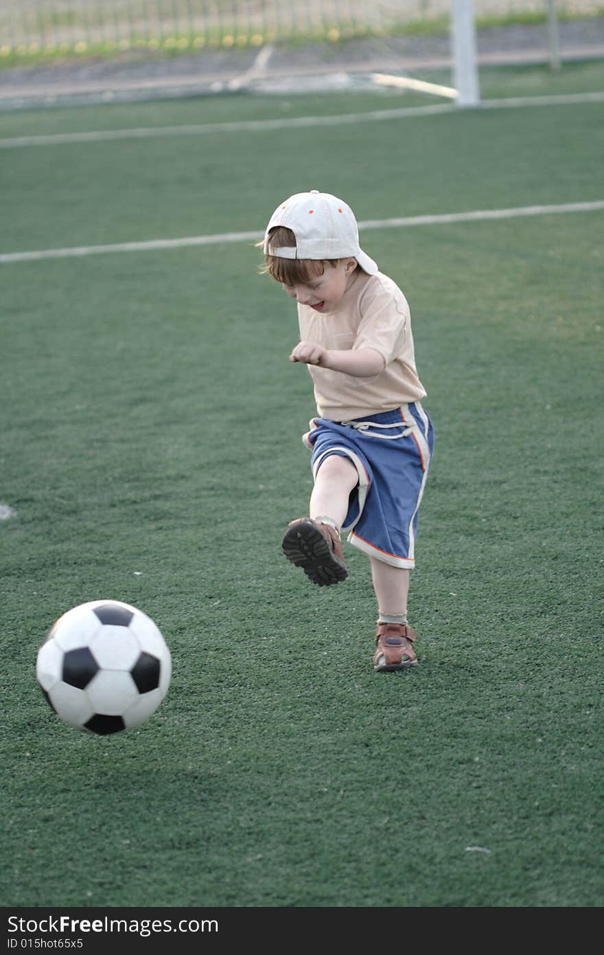 The kid hazardously playing football in stadium