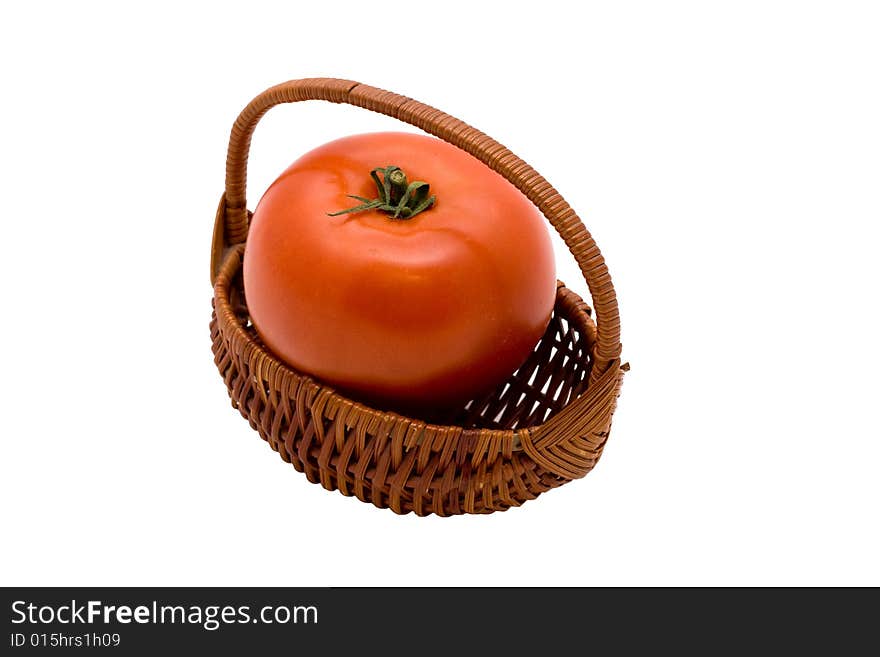 A single fresh red tomato in small wicker basket on isolated white background. A single fresh red tomato in small wicker basket on isolated white background