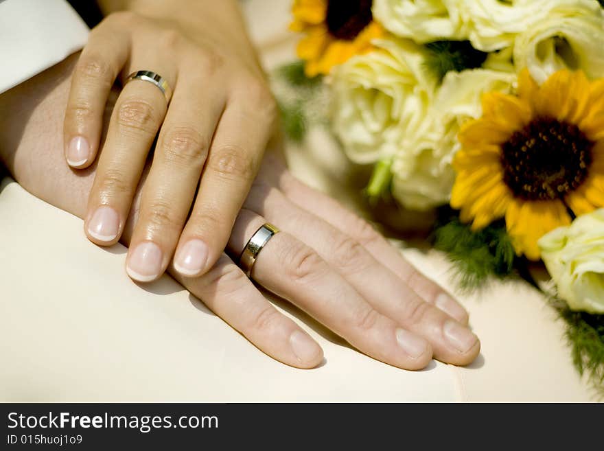 Holding hands of bride and groom with wedding bouquet in the background. Holding hands of bride and groom with wedding bouquet in the background