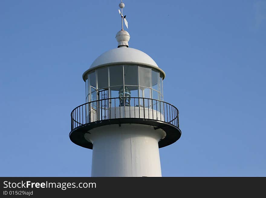 Top of lighthouse with windvane and a bird on top. closeup of freznel lens. balcony around the light. Top of lighthouse with windvane and a bird on top. closeup of freznel lens. balcony around the light