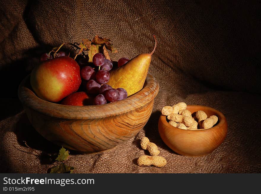 Autumn fruits in wooden cup on burlap background