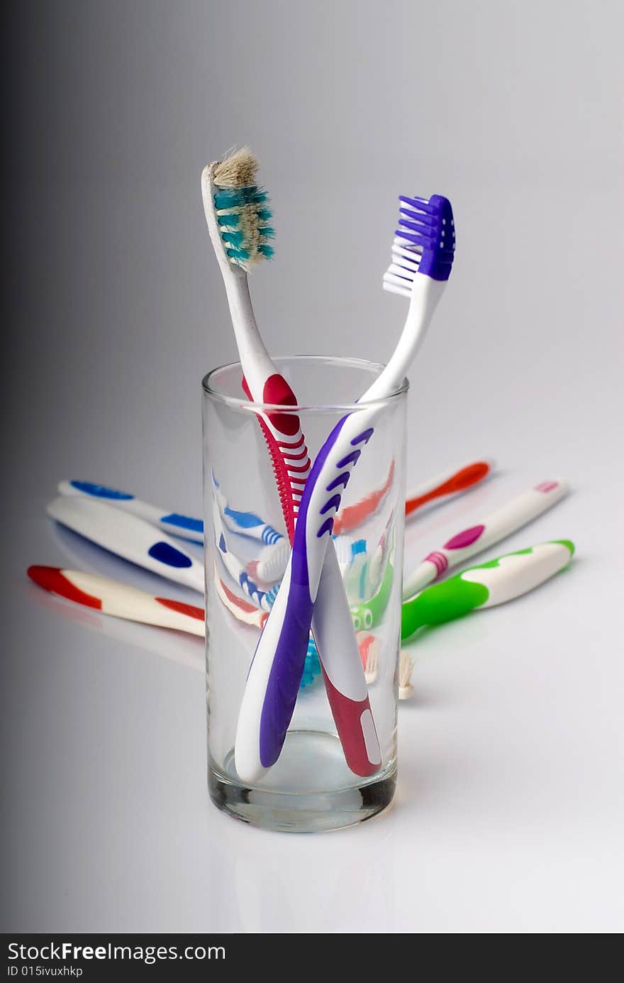 New and old toothbrushes in glass