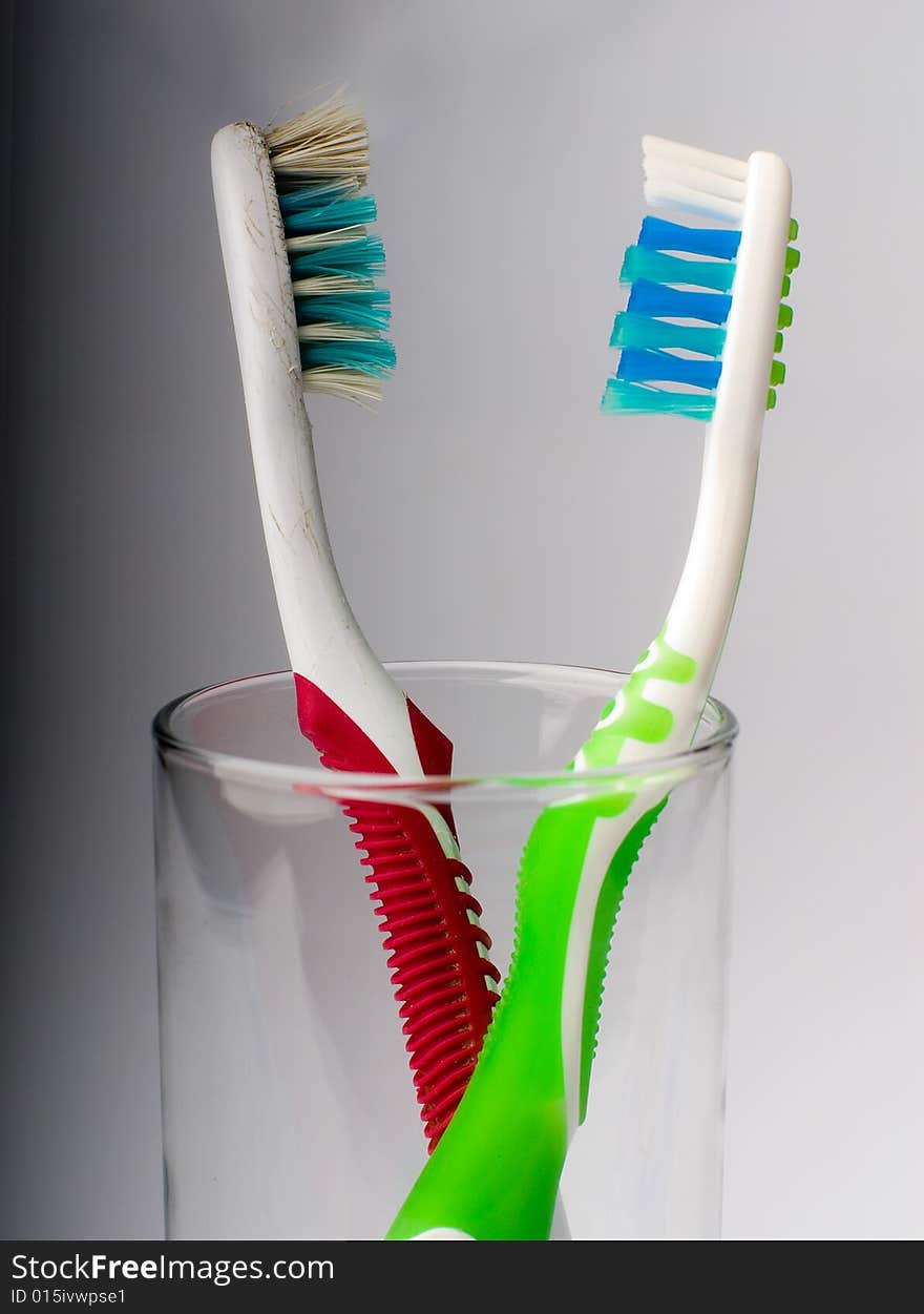 New and old toothbrushes in glass