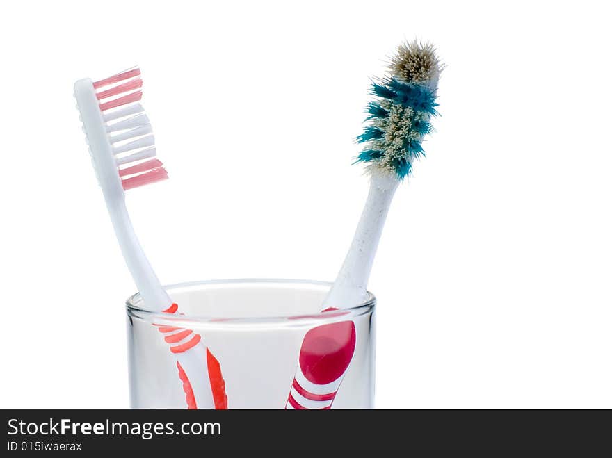 New and old toothbrushes in glass, isolated