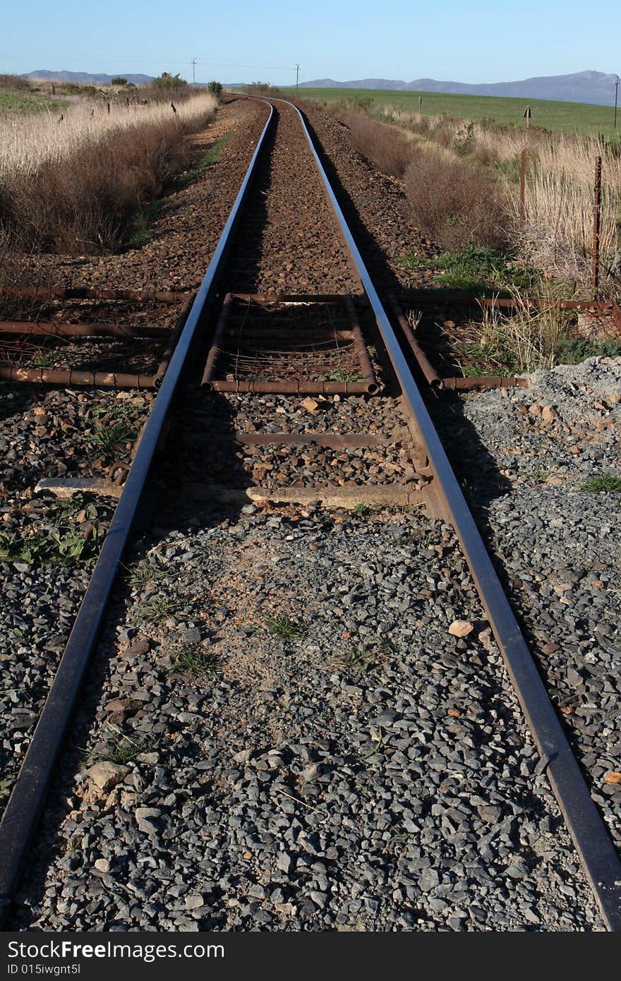 Rural rail road tracks disappearing around a bend.